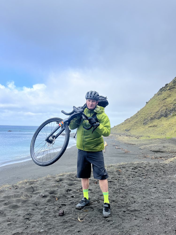 Carrying a gravel bike along the beach on the Remutaka cycle trail, 2025
