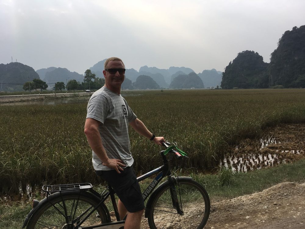 Chris van der Leer cycling through rice fields on a Vietnam bike tour, 2017